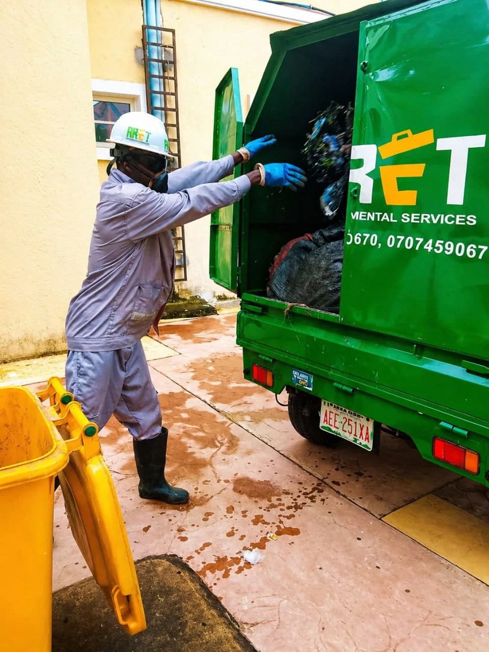ARET field worker loading collected waste into a branded service vehicle